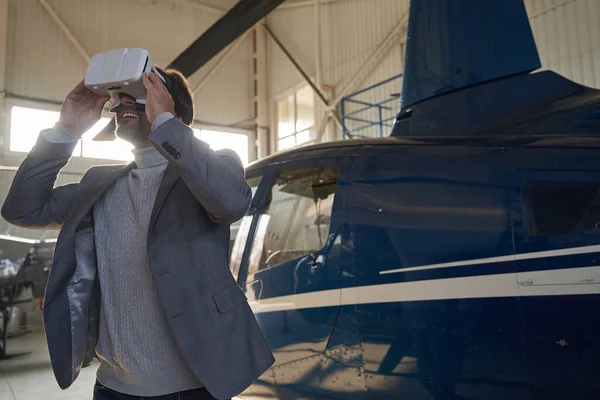 Fröhlicher Mann spielt 3D-Spiel im Flugzeughangar — Stockfoto