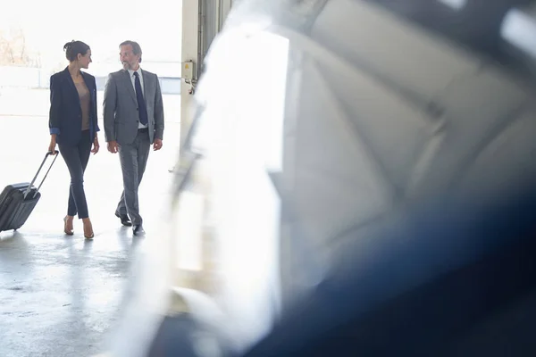 Vrolijke heer en elegante dame met bagage in vliegtuig hangar — Stockfoto