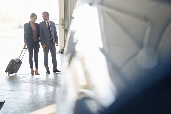 Frau mit Gepäck und ihr männlicher Begleiter im Flugzeughangar — Stockfoto