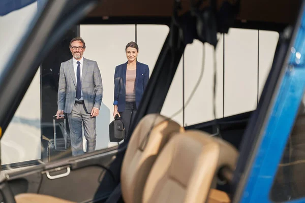 Dois empresários sorridentes com bagagem se aproximando de helicóptero — Fotografia de Stock