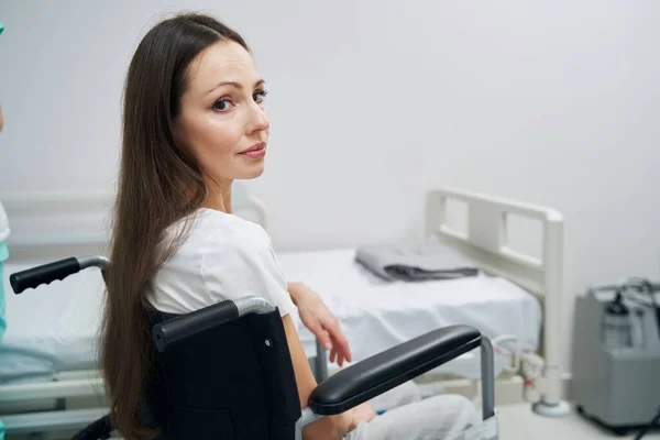 Depressieve vrouw met een handicap zit naast bed in het ziekenhuis afdeling — Stockfoto