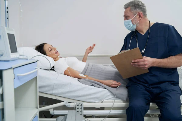 Gioiosa paziente di sesso femminile che comunica con il medico durante la terapia endovenosa — Foto Stock