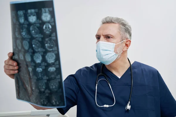 Зосереджений лікар, який вивчає зображення мозку пацієнта — стокове фото