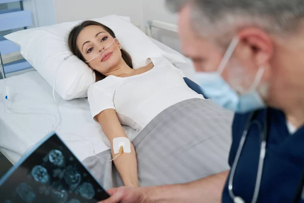 Neurologista focado examinando exames de RM de mulher jovem — Fotografia de Stock