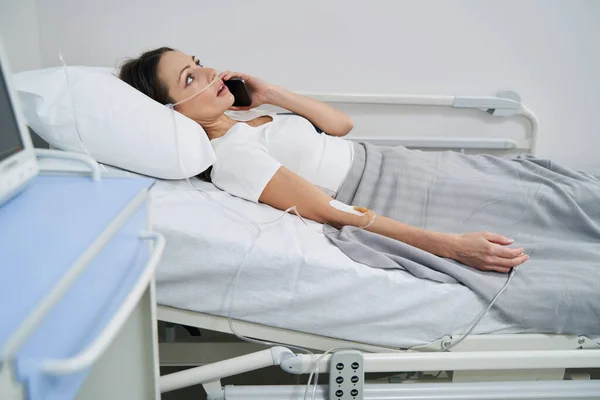 Patient liegt bei Telefonat auf Krankenhausstation im Bett — Stockfoto