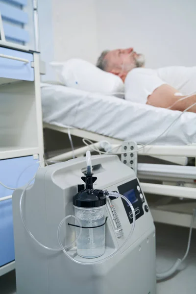 Patient mâle couché connecté à un concentrateur d'oxygène portable — Photo