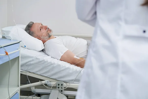 Patient couché regardant fixement le médecin traitant pendant le tour de salle — Photo