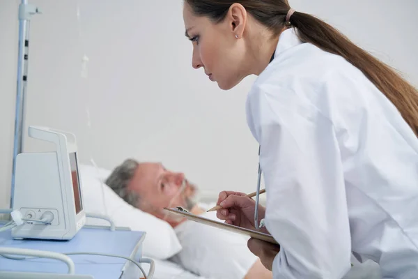 Médico feminino concentrado verificando sinais vitais masculinos — Fotografia de Stock