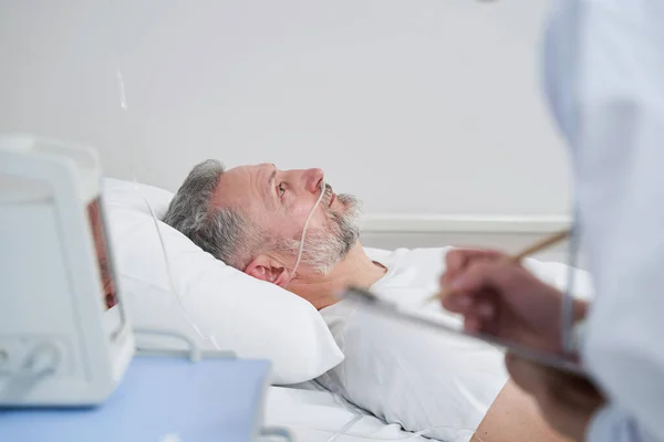 Paciente do sexo masculino sendo visitado pelo médico assistente no hospital — Fotografia de Stock