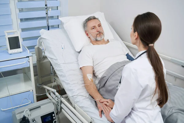 Läkare undersöker mogen man med intravenös infart — Stockfoto