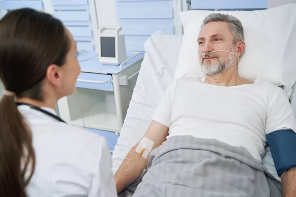 Männlicher Patient kommuniziert während der intravenösen Therapie mit dem Arzt — Stockfoto