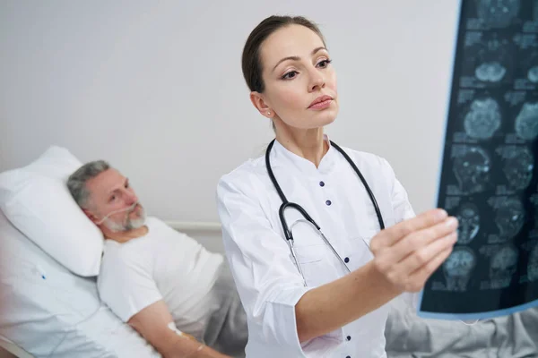 Neurólogo centrado en la calma examinando resonancias magnéticas del paciente masculino — Foto de Stock