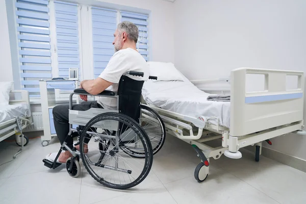 Persona con discapacidad sentada en silla de ruedas en un centro de rehabilitación — Foto de Stock