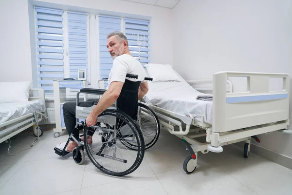 Hombre discapacitado sentado en silla de ruedas en la sala de hospital —  Fotos de Stock