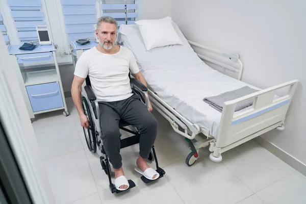 Starší pacient sedí sám na kolečkovém křesle v nemocnici — Stock fotografie