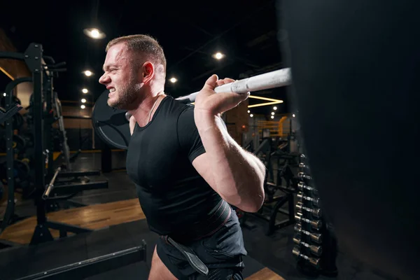 Culturista vigoroso haciendo ejercicio de levantamiento de pesas en el gimnasio —  Fotos de Stock