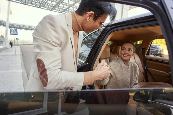 Mujer agradecida saliendo del coche con la ayuda del hombre — Foto de Stock