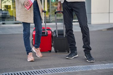 Arkalarında bavulları taşıyan iki kişi var.