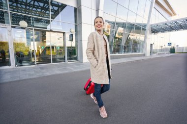 Havaalanından bavulla ayrılan neşeli bayan.