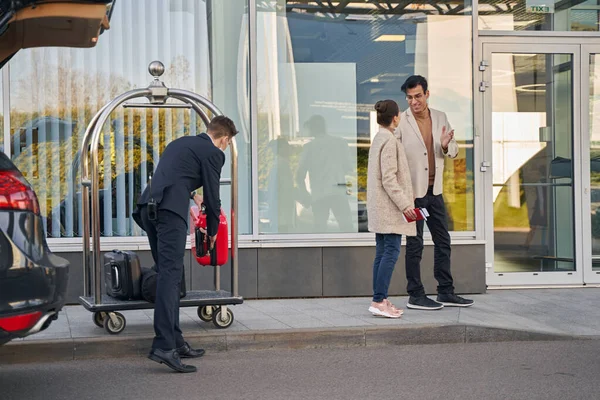 Працівник аеропорту розвантажує пару багажу з кошика — стокове фото