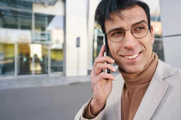 Hombre sonriente en gafas al aire libre hablando en el teléfono inteligente — Foto de Stock