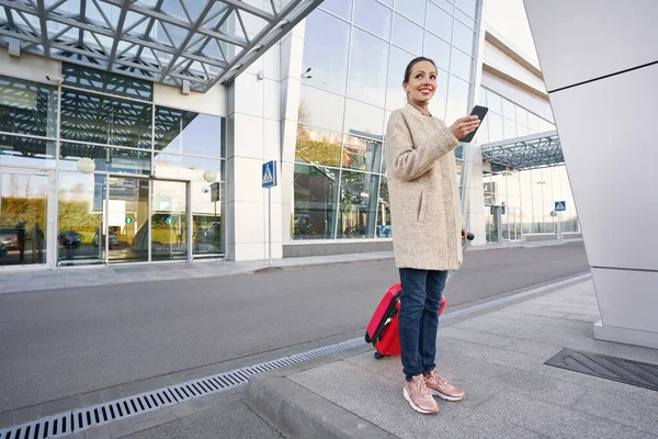 공항 근처에 스마트폰 과 짐을 가지고 있는 여성 여행자 — 스톡 사진