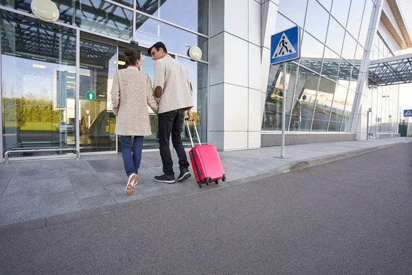 Nő és férfi belépnek a repülőtérre a poggyászukkal — Stock Fotó