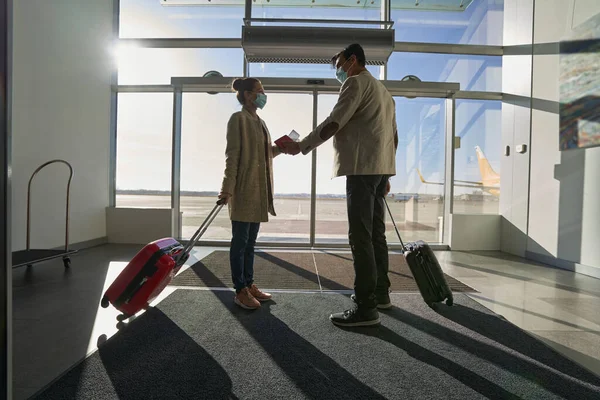 Романтична пара тримає руки, стоячи всередині аеропорту — стокове фото