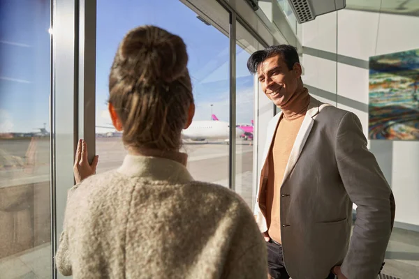 Glücklicher Mann am Flughafenfenster blickt Frau an — Stockfoto