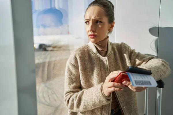 Zaniepokojona kobieta z biletem lotniczym i telefonem — Zdjęcie stockowe