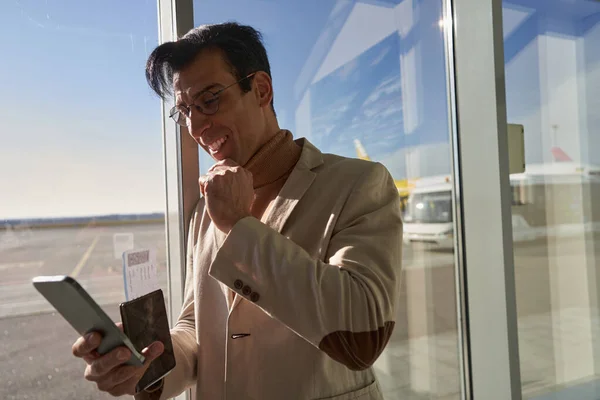 Man väntar på flyg med smartphone nära fönstret — Stockfoto