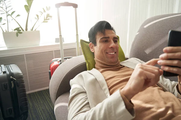 用手机坐在沙发上的快乐男人 — 图库照片