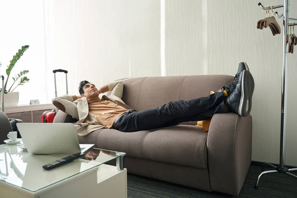 Чоловік розслабляється в готельному номері на дивані — стокове фото