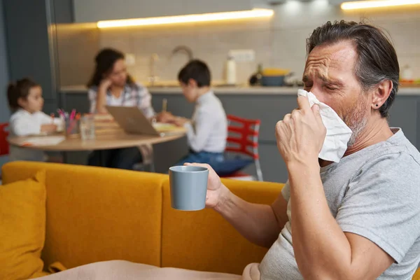 Homem com chá sofrendo de doença soprando o nariz — Fotografia de Stock