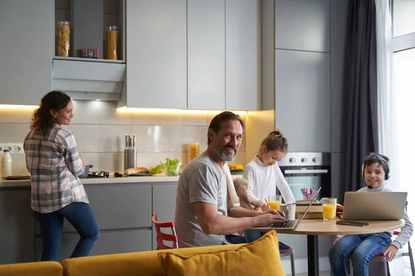 Man zit voor laptop in de keuken met familie — Stockfoto