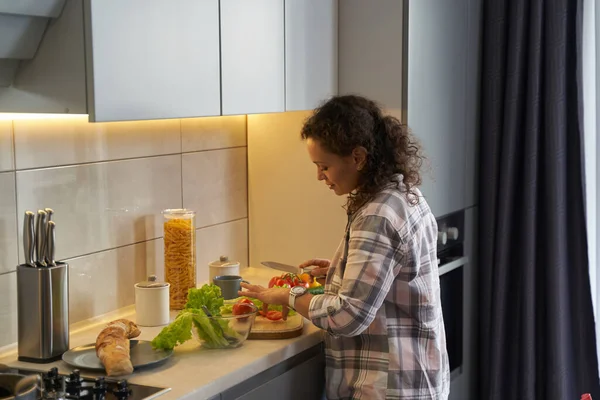 Nő a konyhában főzés saláta az asztalon — Stock Fotó