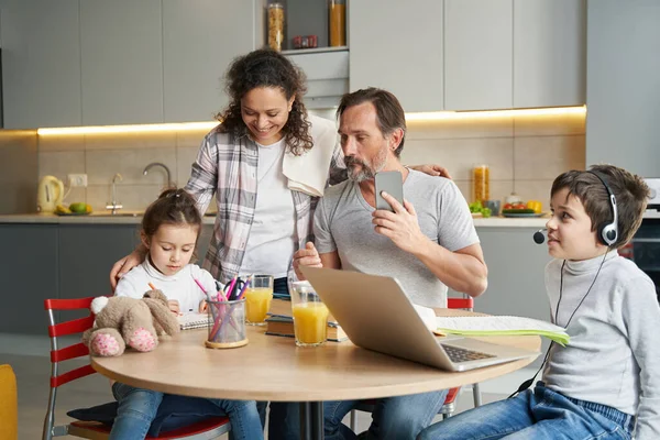 Familia mirando a su hija pintando en la cocina — Foto de Stock