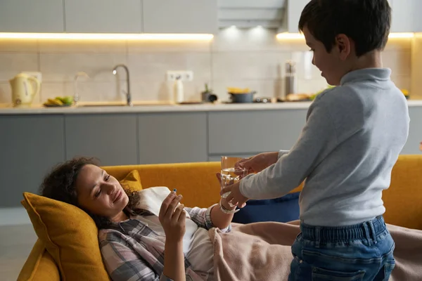 Agradecida madre tomando un vaso de agua de su hijo —  Fotos de Stock