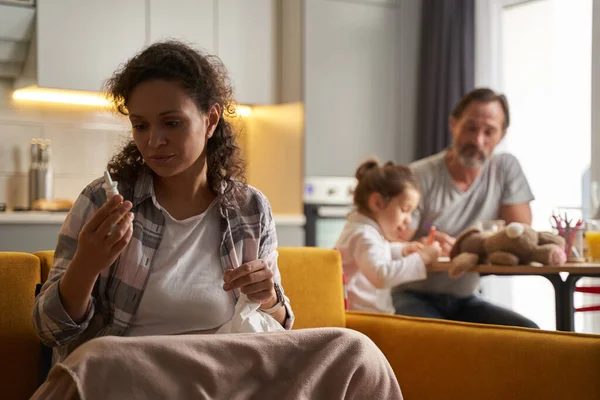 Verontrustende vrouw op bank kijkend naar neusdruppels — Stockfoto