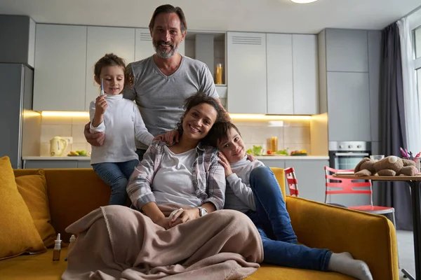 Família feliz sorrindo para a câmera do sofá — Fotografia de Stock