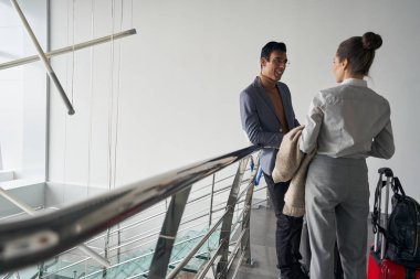 Gülümseyen beyefendi bagajlı bayanla konuşuyor.