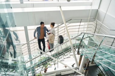 Cam merdivenlerde duran bagajlı turist çifti.