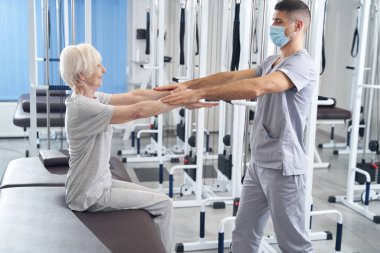 El terapisti avuçlarını emeklilerin ellerine koyuyor.