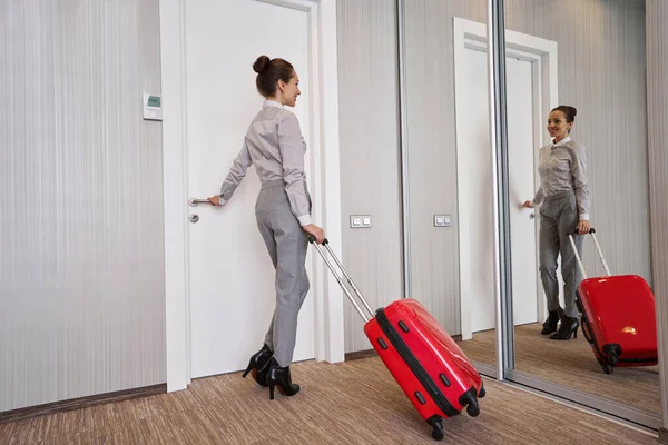 Vrouwelijke toerist staat voor gespiegelde kastdeur in hotelkamer — Stockfoto