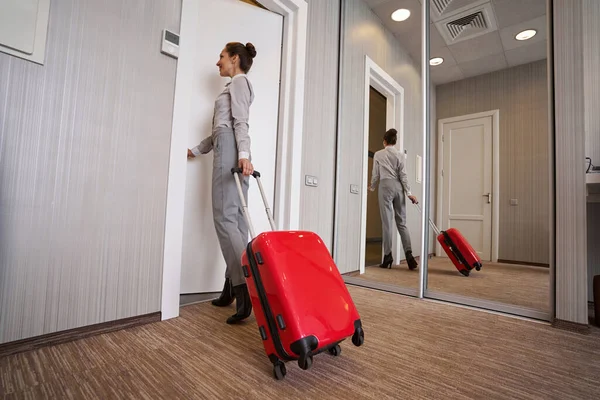 Señora con la maleta del carro saliendo de la habitación del hotel — Foto de Stock