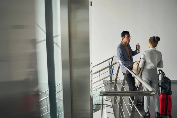 Homme avec documents de voyage parlant à une femme dans le couloir — Photo