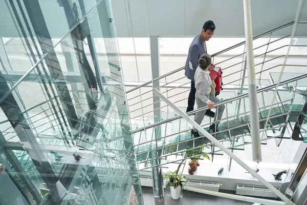 Couple avec documents de voyage montant des escaliers en verre — Photo