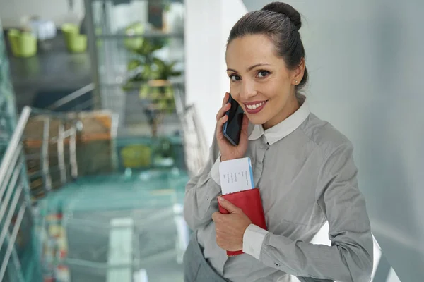 Pleased stylish lady with travel documents talking on smartphone — Stock Photo, Image