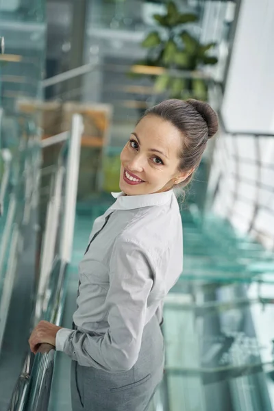 Joyful female posing for camera on glass staircase — Stock Photo, Image