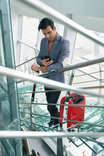 Geconcentreerde man die sms 'jes leest op zijn telefoon op de trap — Stockfoto